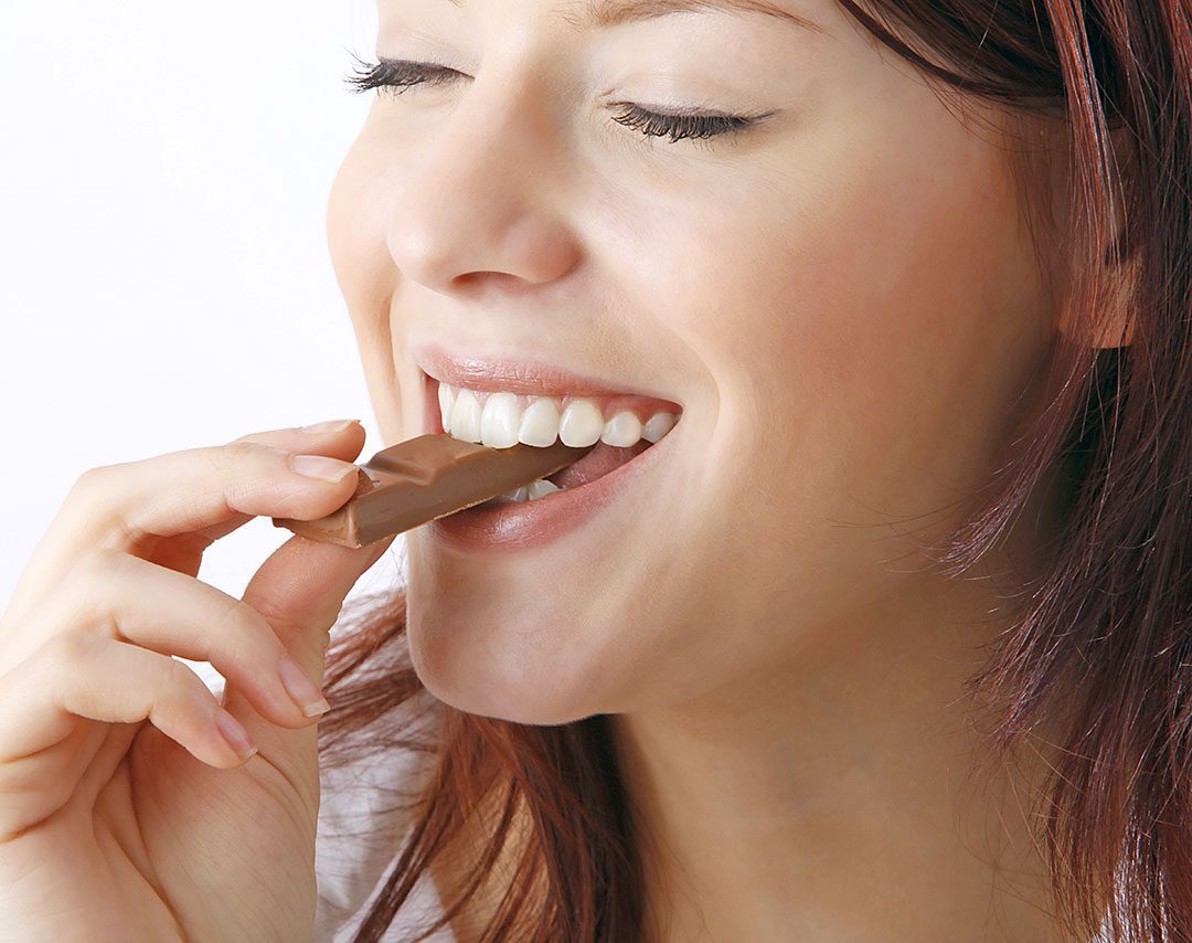 Woman Smiling Eating Chocolate Bar